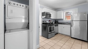 A compact kitchen with a built-in washer and dryer, stainless steel appliances, and a tiled floor.