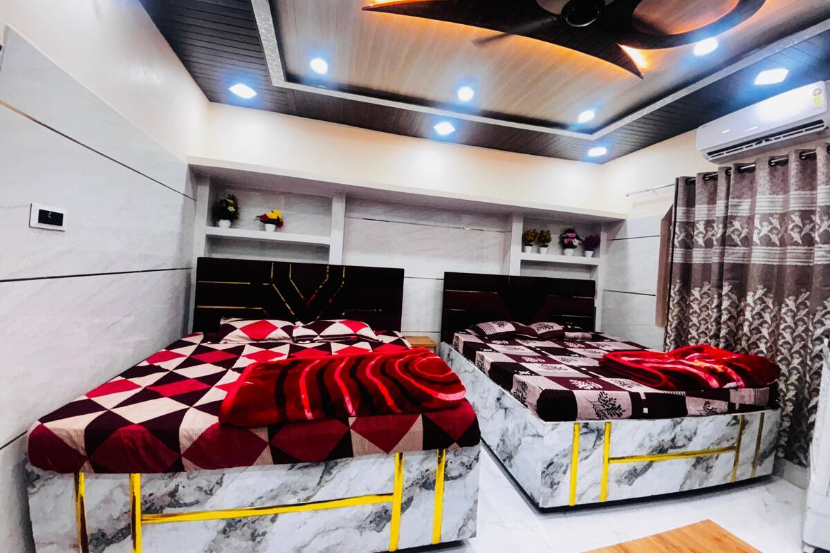 Un dormitorio moderno con dos camas, cabeceros de mármol y estanterías empotradas decoradas con objetos ornamentales.
