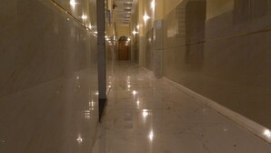 A long, narrow hallway with reflective floors and walls, leading to a door at the end. - Vatsalya Bhawan Ayodhya (Faizabad)