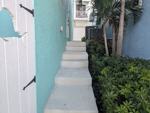 Stroll up to this tropical retreat, featuring a balcony with a railing and air conditioning units.