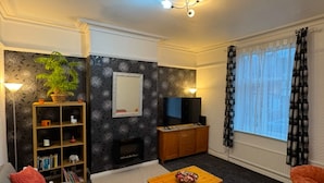 Una sala de estar con chimenea, televisor, mesa de centro y sofá.