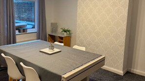Un comedor con mesa, sillas y una ventana con cortinas.