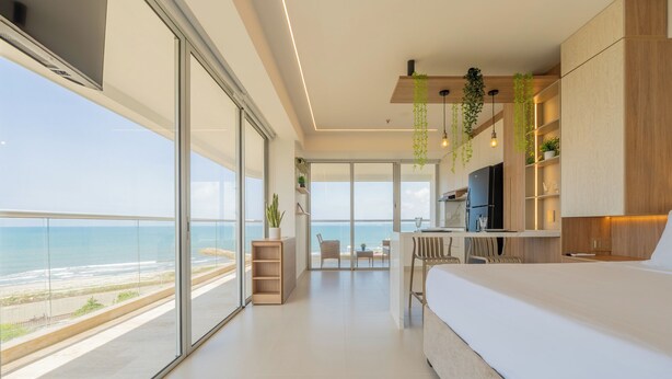 Un dormitorio moderno con una cama grande, un escritorio y vista al océano.
