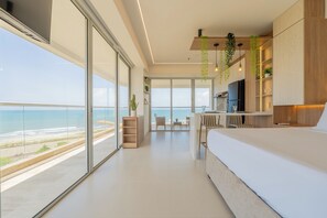 Quarto moderno com uma cama grande, uma escrivaninha e vista para o oceano.