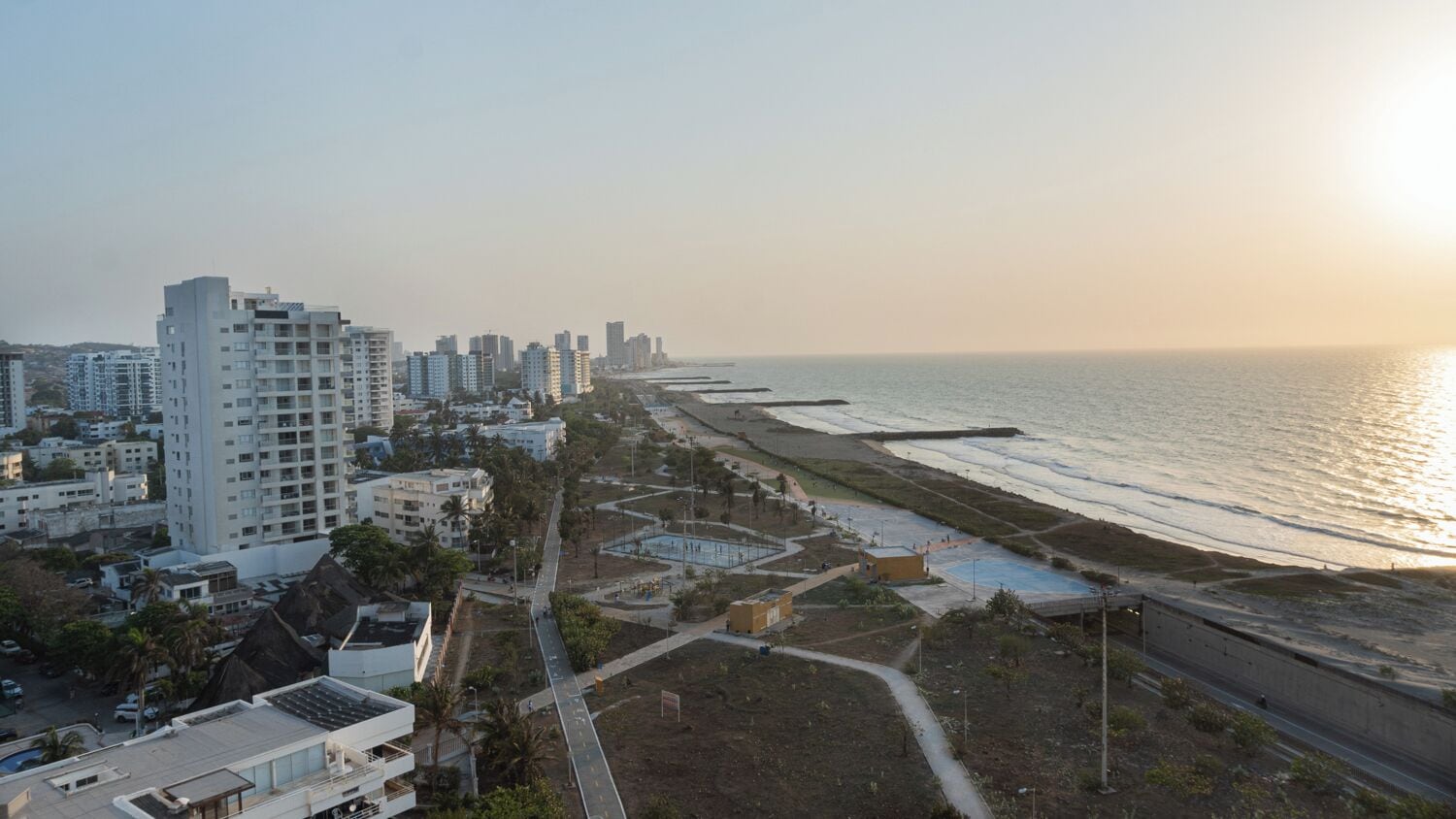Un paysage urbain côtier avec de hauts immeubles, une plage et un ciel dégagé.
