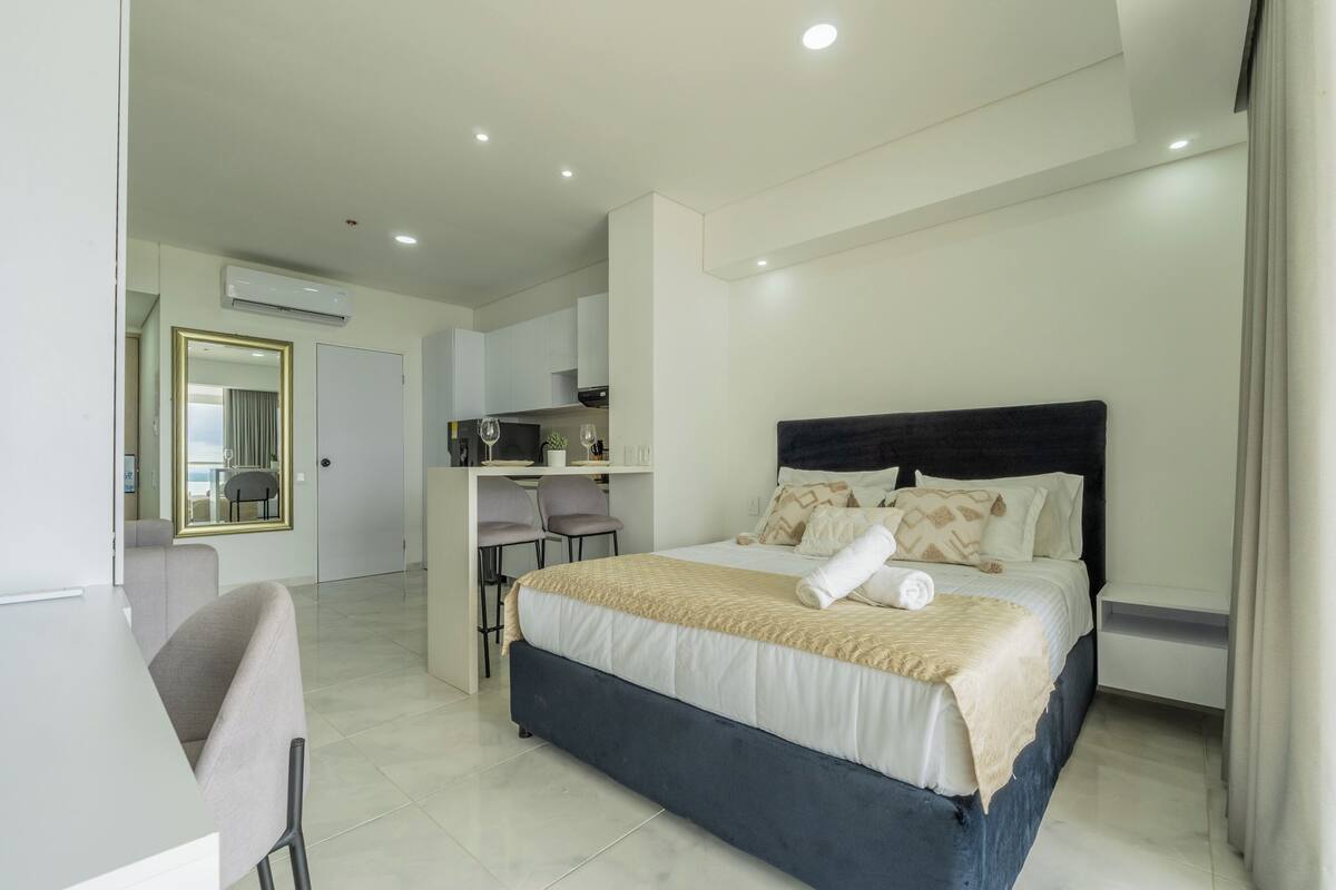 A modern hotel room with a large bed, a desk, and a chair.