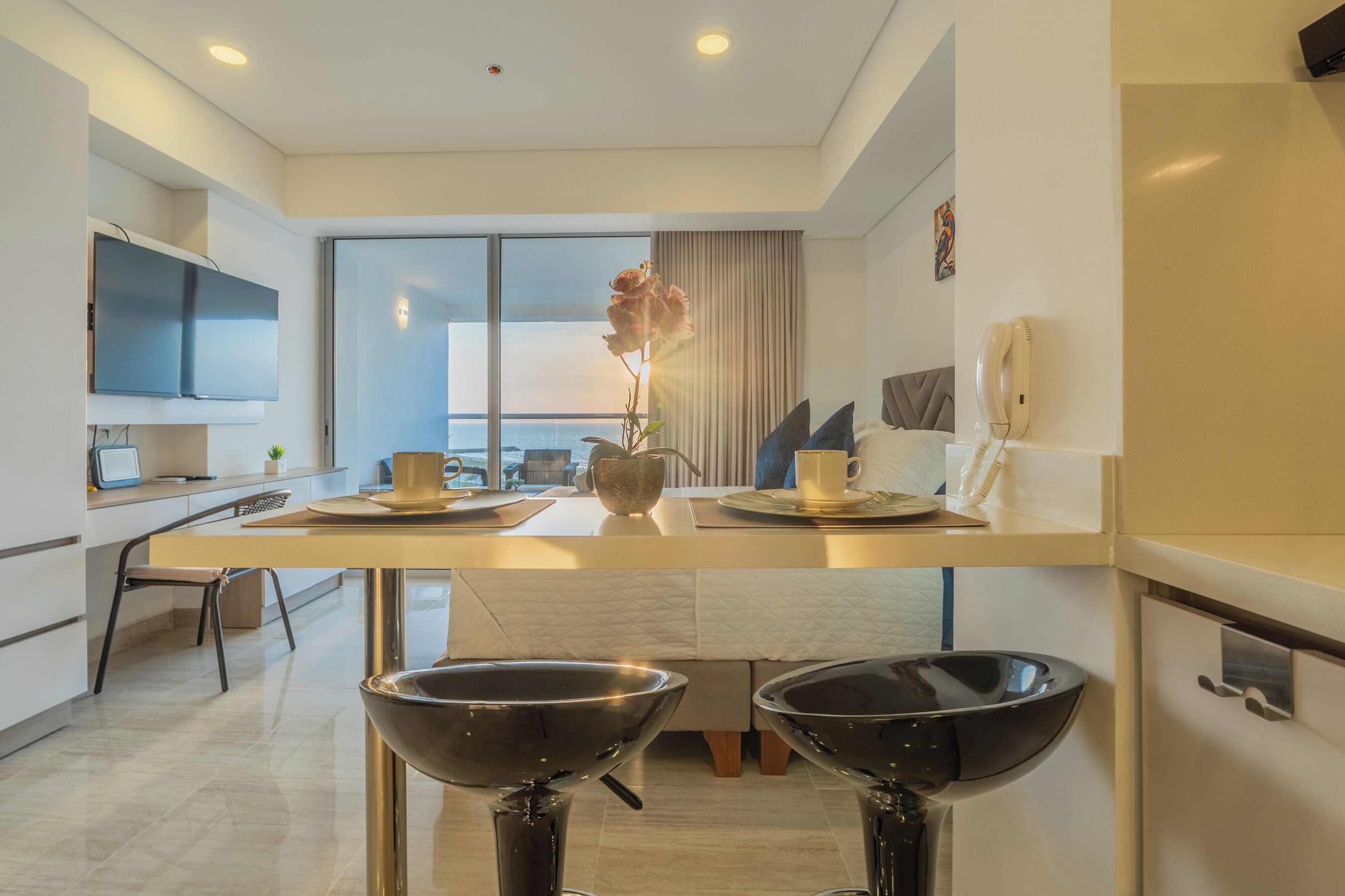 Una cocina moderna con comedor, un ventanal grande y un televisor de pantalla plana.