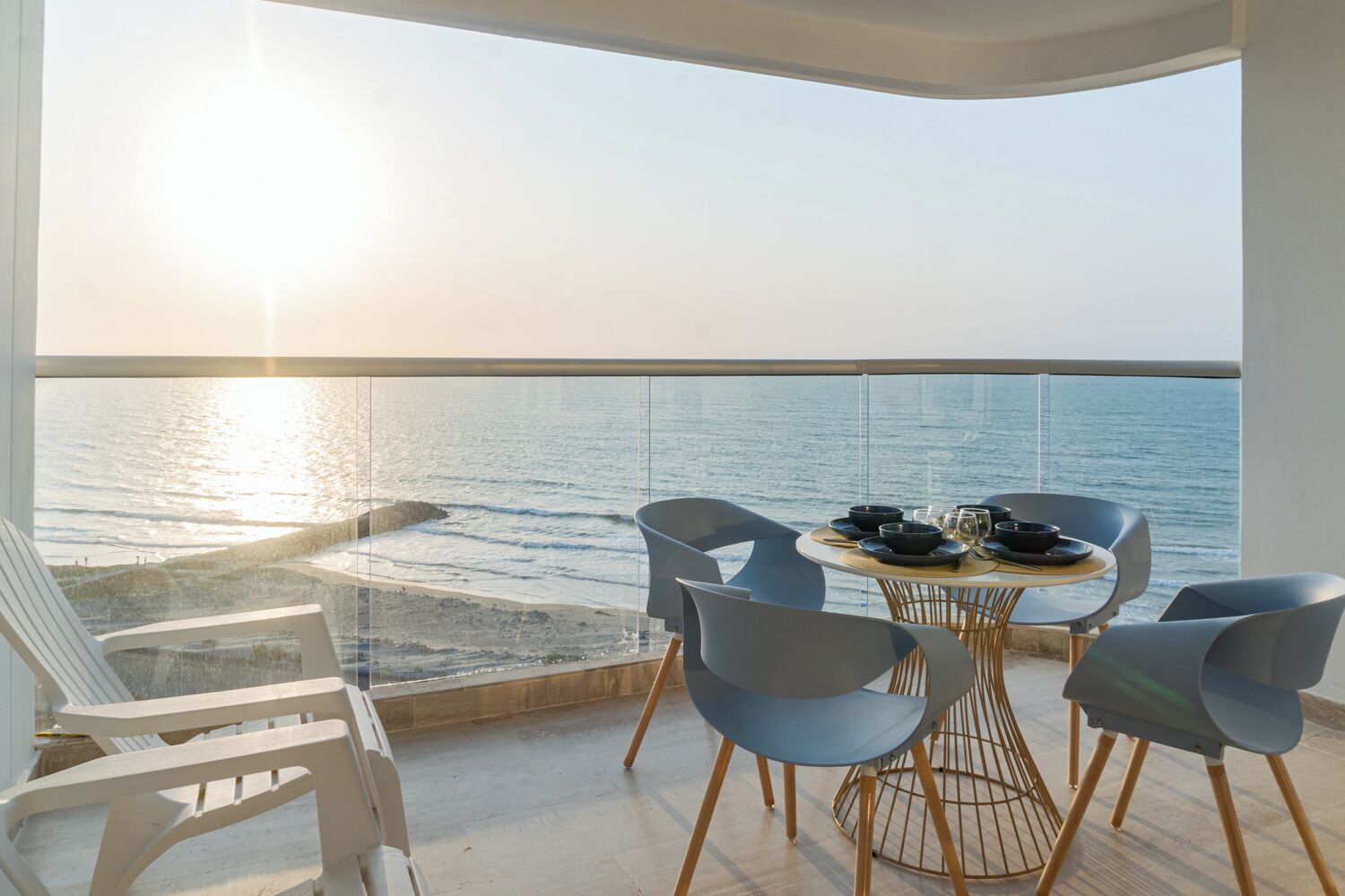 Een balkon met een eettafel, met uitzicht op een strand en de oceaan.