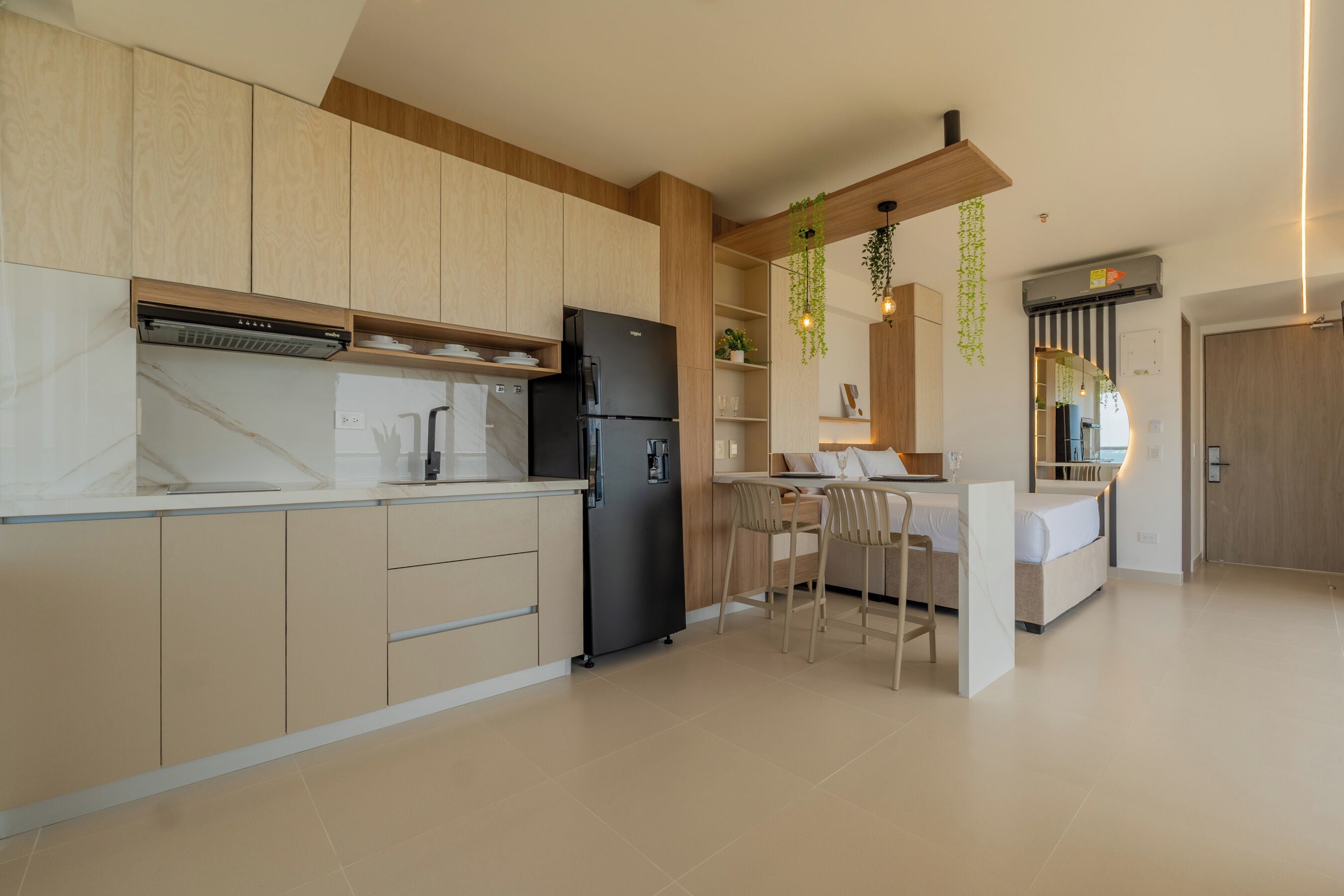 A modern kitchen with wooden cabinets, a black refrigerator, and a dining area with a table and chairs.