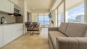 Una cocina moderna con armarios blancos, una campana extractora negra y un comedor con mesa y sillas.