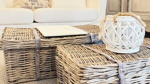 A living room with a white sofa, a decorative lamp, and wicker baskets.