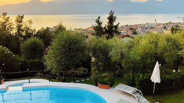 A swimming pool with a view of a town and mountains in the background.