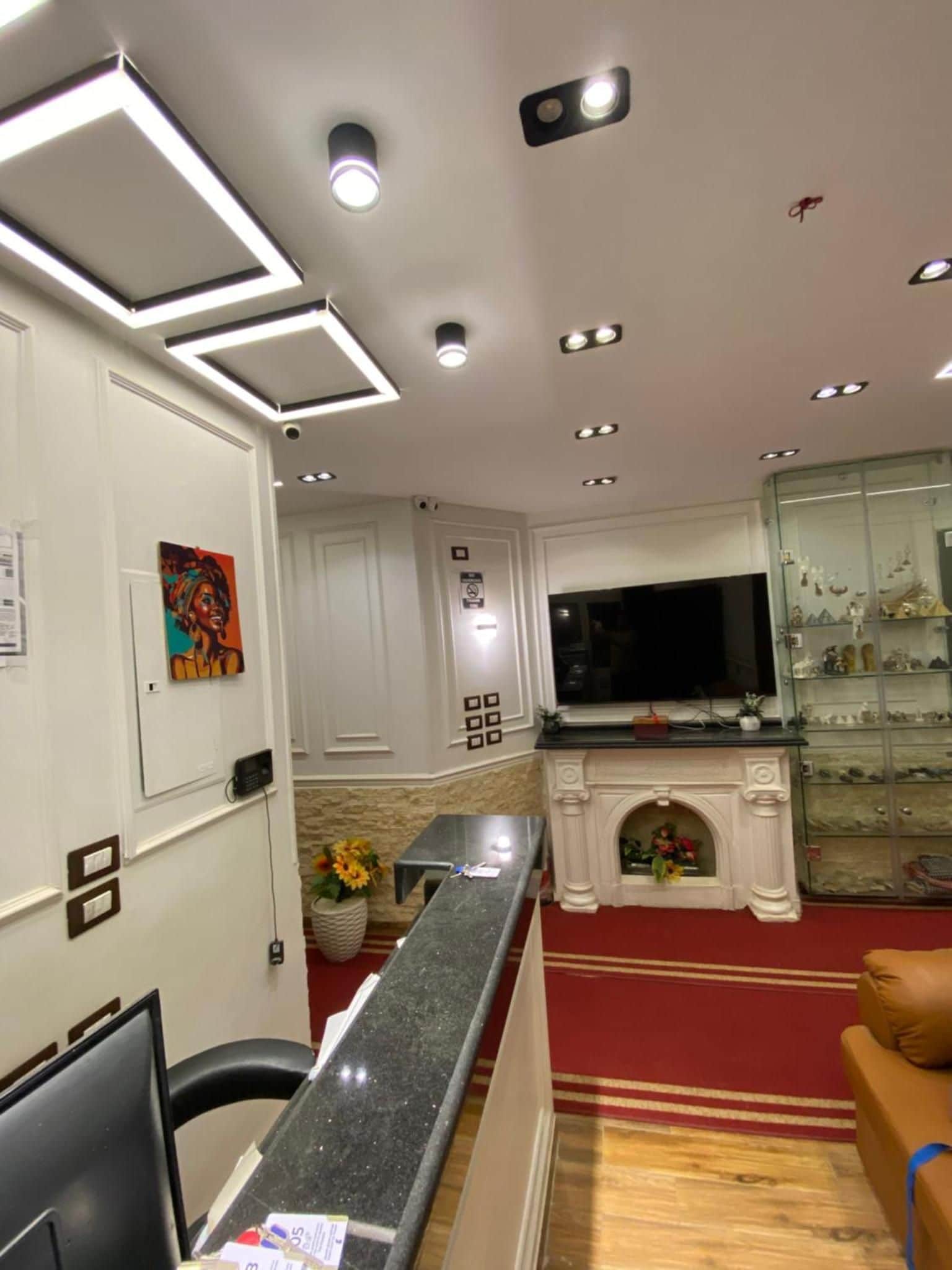 Eine Hotelhalle mit Empfangstresen, Kamin, Fernseher und Ausstellungsstücken auf Regalen.