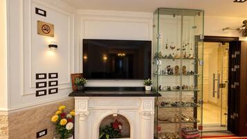 A hotel lobby with a fireplace, a glass display case with decorative items, and a red carpet.