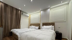 A double bed with a tufted headboard, a bedside table, and a wall-mounted air conditioner. - New White Pyramids Inn (Giza)