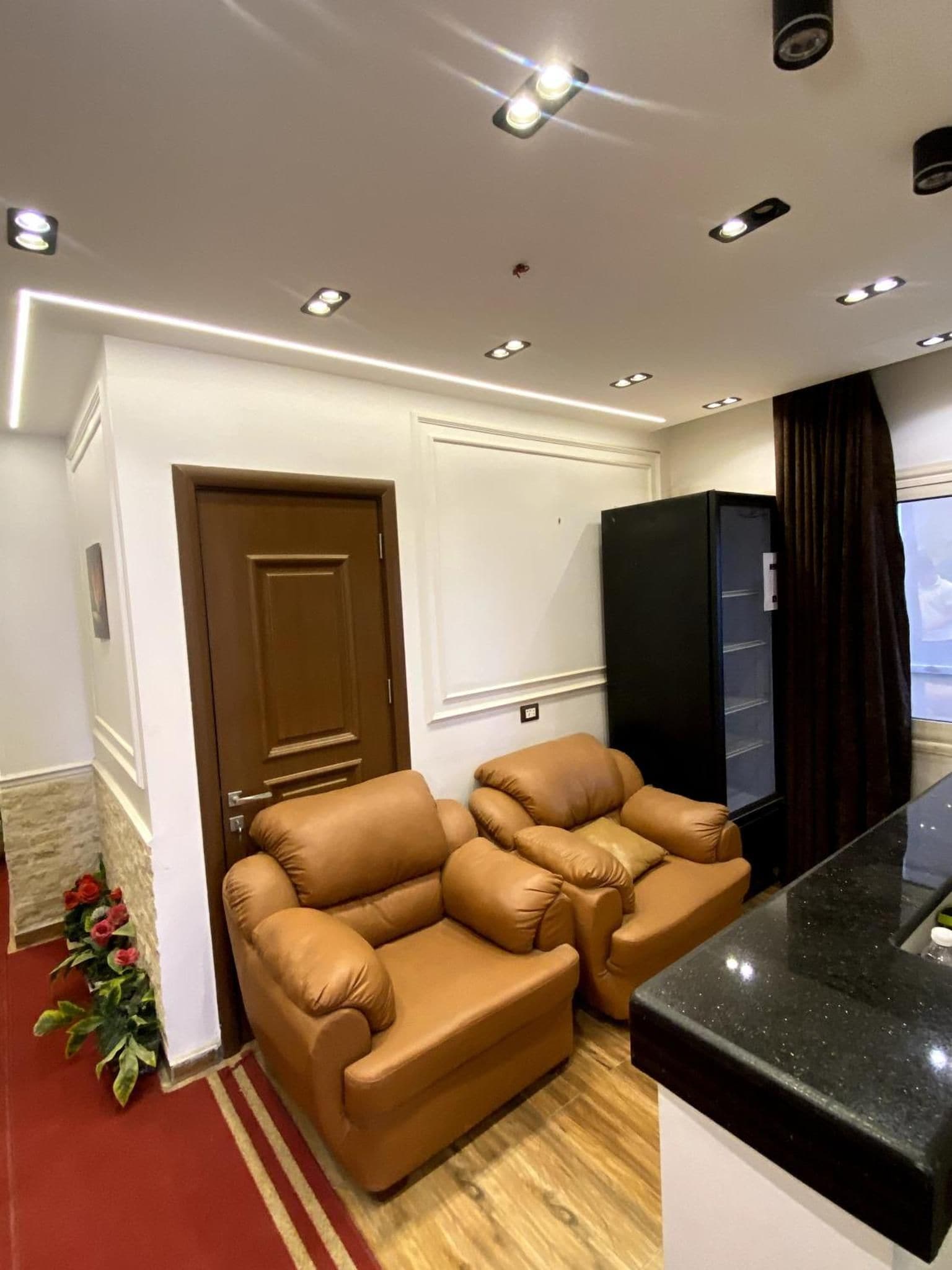 A modern living room with a sofa, a black cabinet, and recessed ceiling lighting.