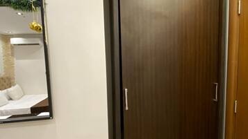 A room with a wooden door, a mirror on the wall, and a small trash bin.
