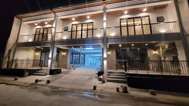 Un immeuble de deux étages, doté d’un balcon à chaque niveau, d’une entrée abritée et d’une façade bien éclairée.