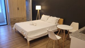 Une chambre d’hôtel moderne comprenant un lit, une table de chevet, une chaise et une petite table ronde.