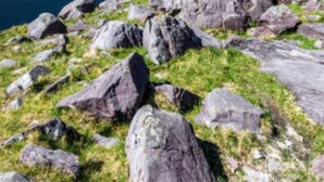 Un paisaje montañoso con un lago y rocas dispersas.