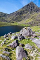 Un paisaje montañoso con un lago y rocas dispersas.