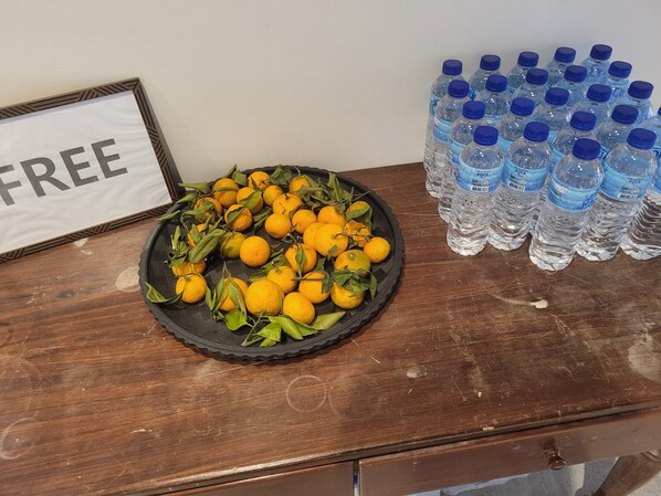 Una mesa de madera con un plato de limones y una pila de botellas de agua.