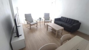 A living room with a sofa, two armchairs, a coffee table, and a TV on a stand.