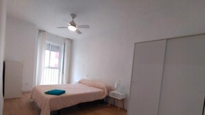 A bedroom with a bed, a nightstand, a ceiling fan, and a wardrobe.