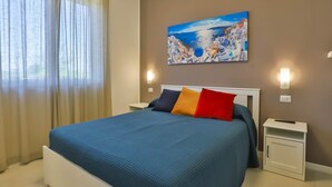 Un dormitorio con una cama, un cuadro y una mesita de noche.