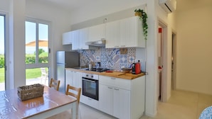 Una cocina con armarios blancos, salpicadero de azulejos y vistas al exterior.