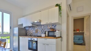 A modern kitchen with white cabinets, a patterned backsplash, a microwave, and an oven.