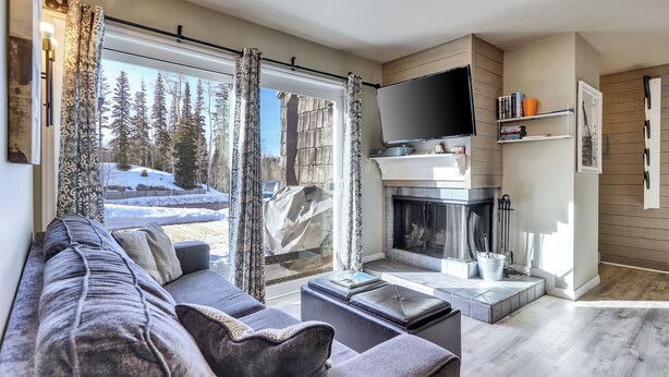 A modern living room with a fireplace, a large flat-screen TV, and a cozy seating area. - Mountain Nest Retreat Ground Level Condo Brian Head (Brian Head)