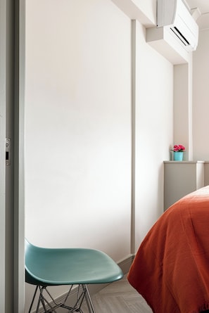 A modern room with a teal chair, a red blanket, and a white air conditioning unit. - Lux Regents Park 2 bed 2 bath flat with AC (London)