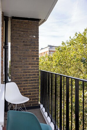 A balcony with a brick wall, a black railing, and two chairs. - Lux Regents Park 2 bed 2 bath flat with AC (London)