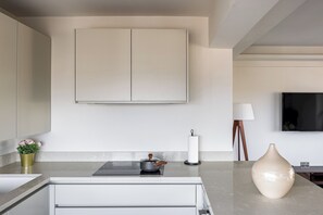 A modern kitchen with a marble countertop, a stove, a vase, and a flat-screen TV mounted on the wall. - Lux Regents Park 2 bed 2 bath flat with AC (London)