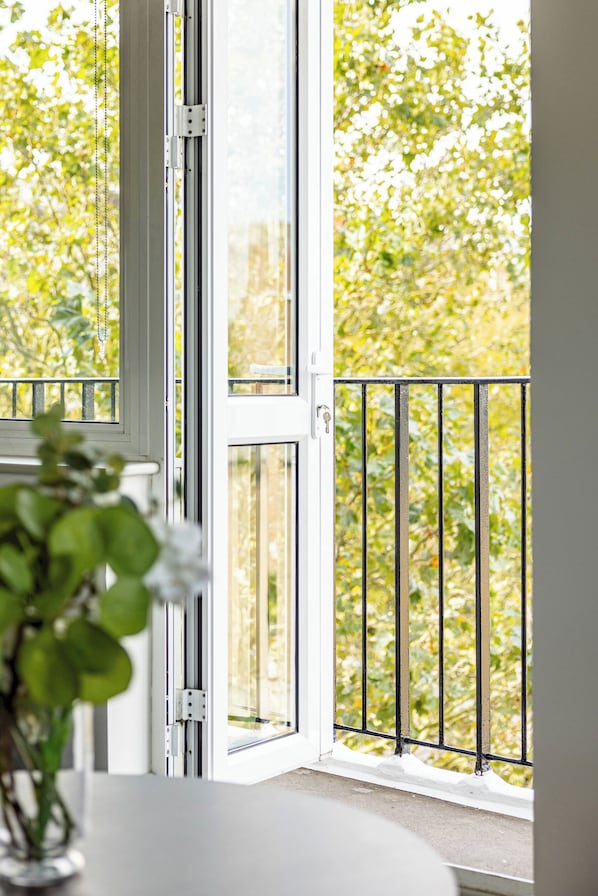 A balcony with a metal railing, a sliding glass door, and a view of greenery outside. - Lux Regents Park 2 bed 2 bath flat with AC (London)