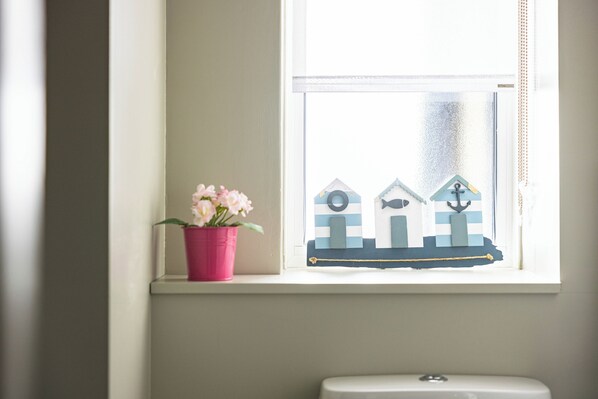 A window with a nautical-themed decoration, a potted plant, and a toilet visible below. - Lux Regents Park 2 bed 2 bath flat with AC (London)
