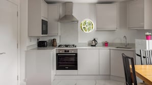 A compact kitchen with white cabinetry, a built-in oven, a microwave, and a gas stove. - Picktheplace Kensington Lux Apartments III (London)