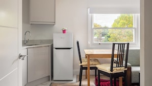 A compact kitchen with a refrigerator, a sink, and a window with a view of trees. - Picktheplace Kensington Lux Apartments III (London)