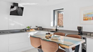 A modern kitchen with a central island, white cabinetry, and a large window providing a view of the outdoors. - Estuary View -  Secure Parking - Nearby Beach (Teignmouth)