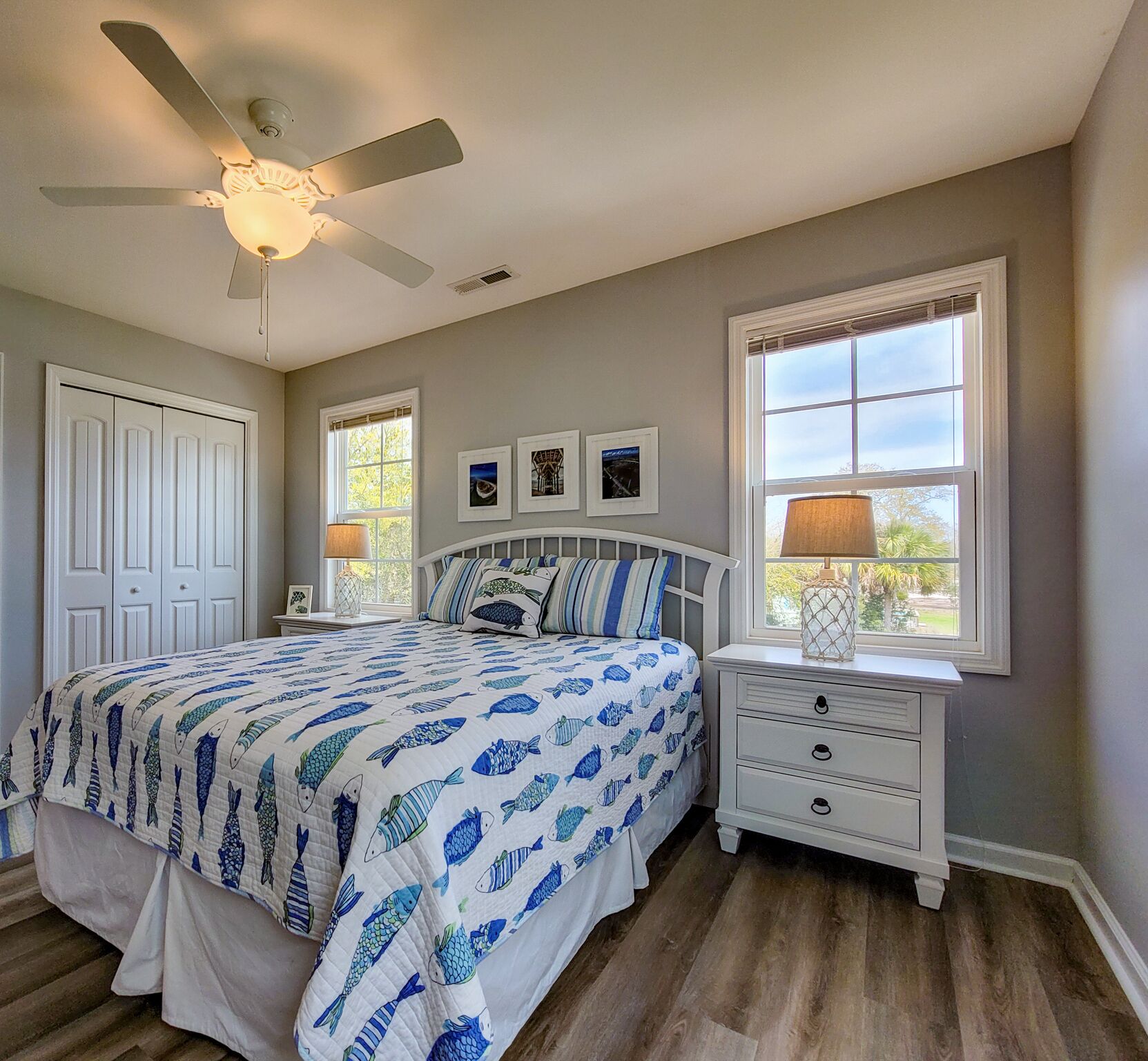A bedroom with a bed, a nightstand, a ceiling fan, and a window with blinds.