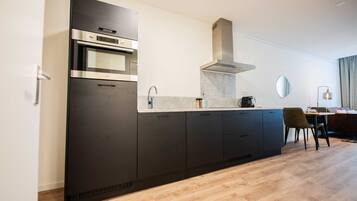 Een koelkast, een oven, een vaatwasser, kookgerei, borden en bestek