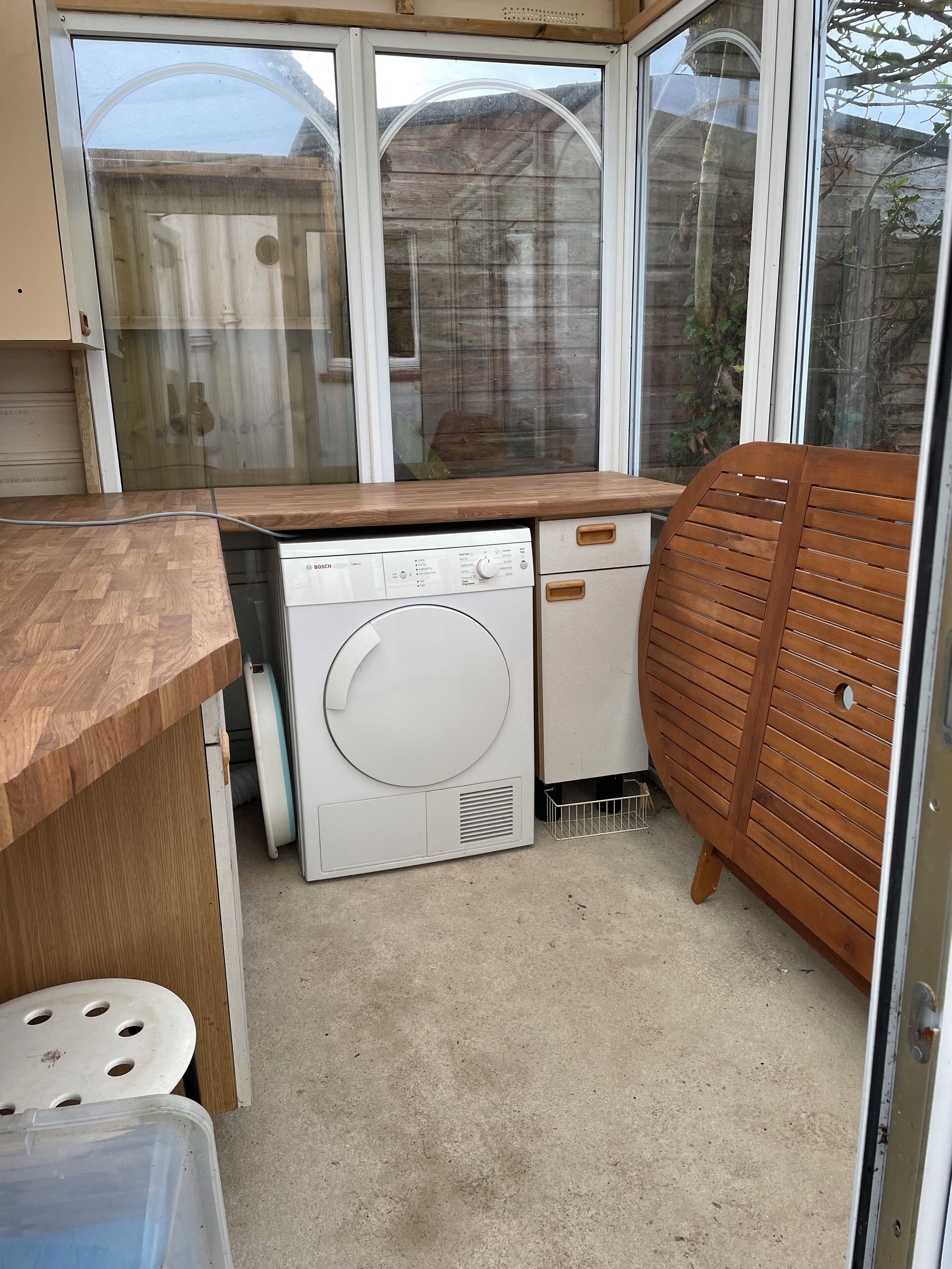 Cocina compacta con lavavajillas Bosch, encimera de madera y una silla de madera.