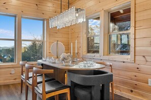 Enjoy meals in this cozy cabin's dining area, featuring a large round table and comfortable seating for all.