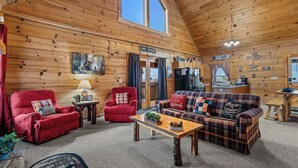 A cozy cabin interior with a wooden interior, a fireplace, a dining area, and a kitchen. - A Lake Resort Property with Stunning Views (Sevierville)