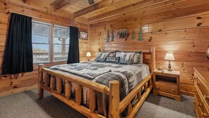 A wooden cabin bedroom with a bed, nightstands, and a ceiling fan. - A Lake Resort Property with Stunning Views (Sevierville)