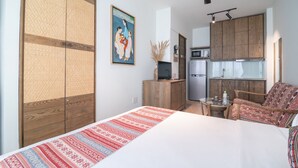 Une chambre d’hôtel de taille réduite, comprenant un lit, un petit bureau, une chaise et une kitchenette.