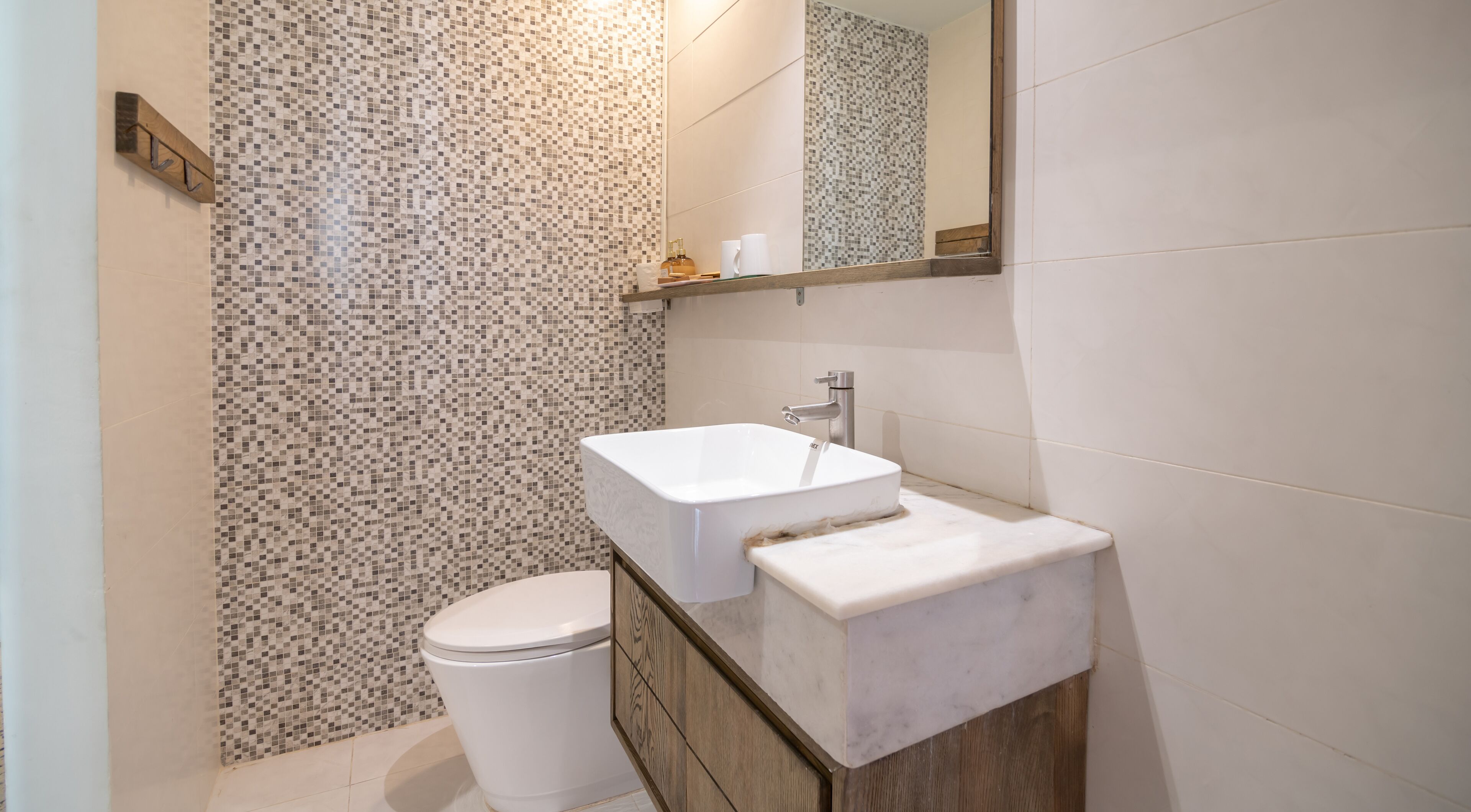 A bathroom with a white toilet, a rectangular sink, and a tiled backsplash.