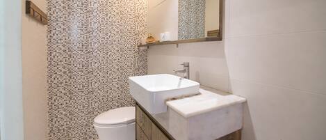 A bathroom with a white toilet, a rectangular sink, and a tiled backsplash.