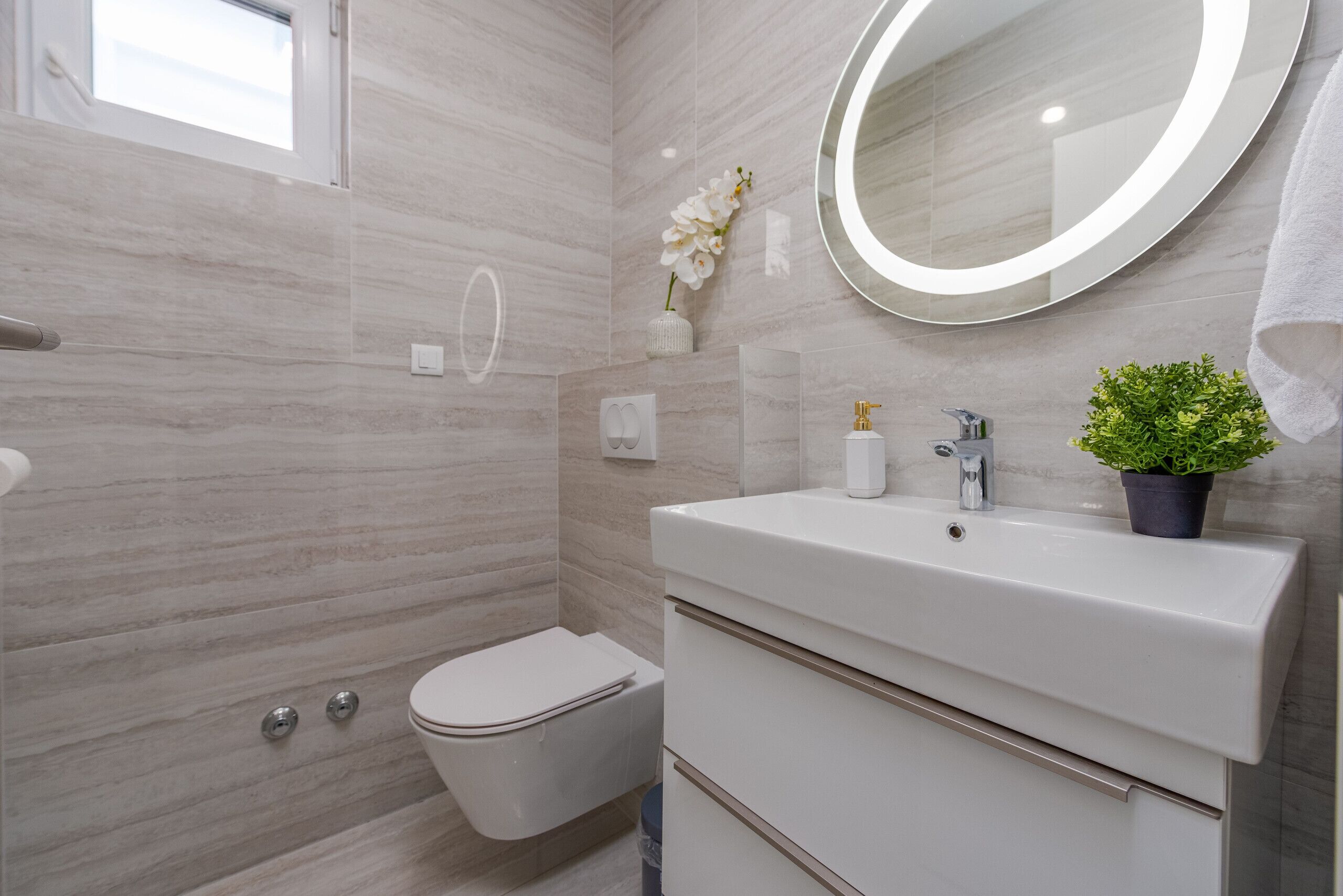 Une salle de bain moderne avec des toilettes, un lavabo et un miroir.